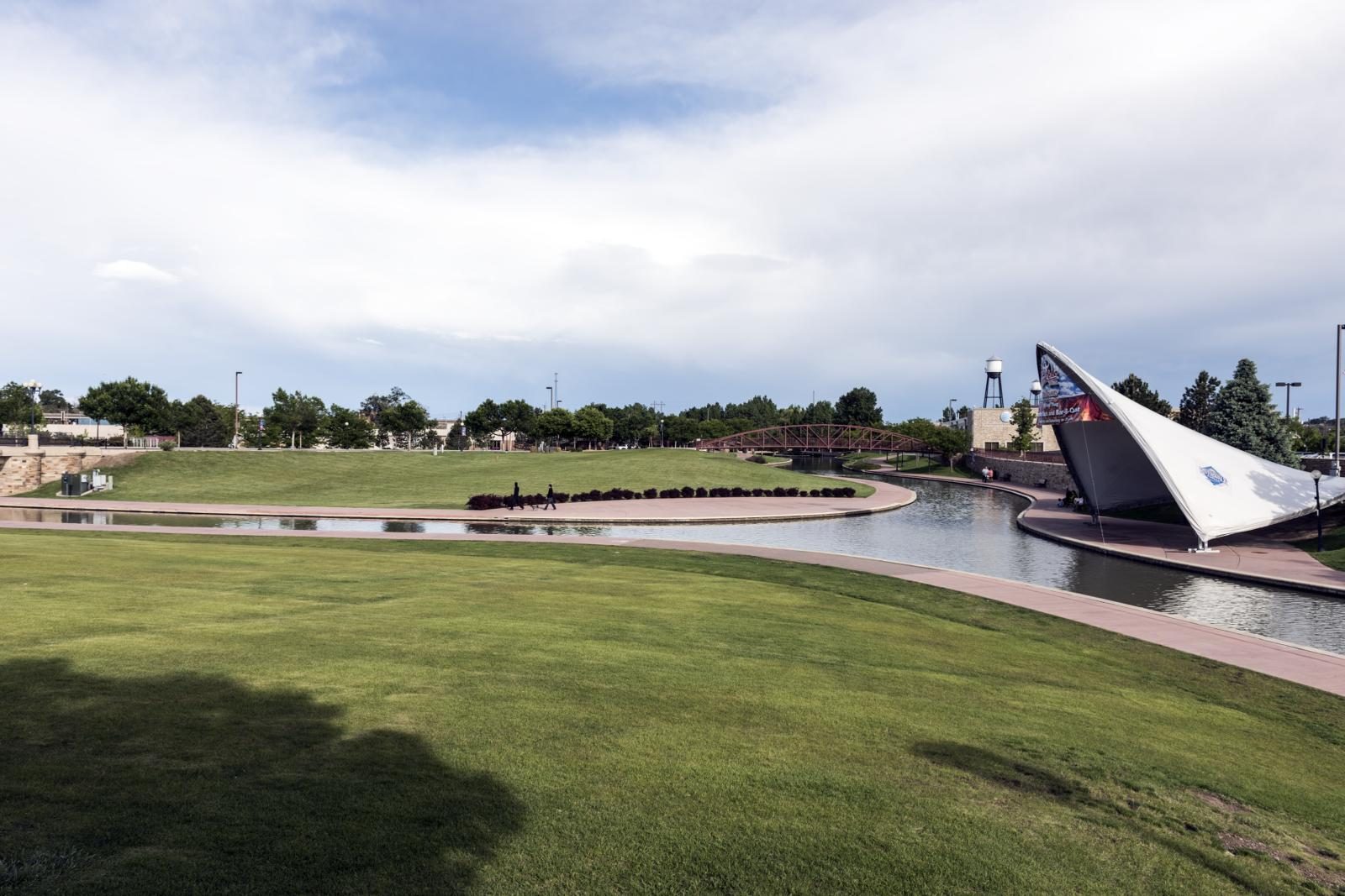 The riverwalk lawn with a pedestrian bridge and amphitheater canopy